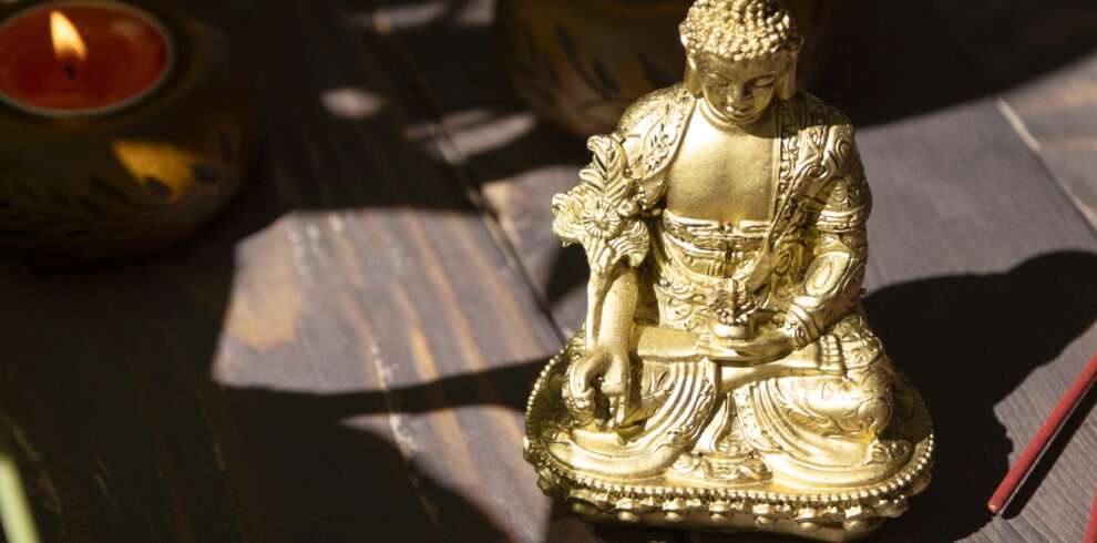 Golden Buddha statue seating in a meditative pose surrounded by candles
