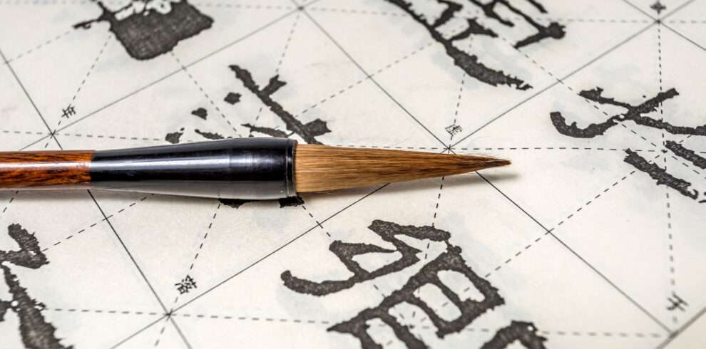 Paint brush on a piece of paper where Kanji are written